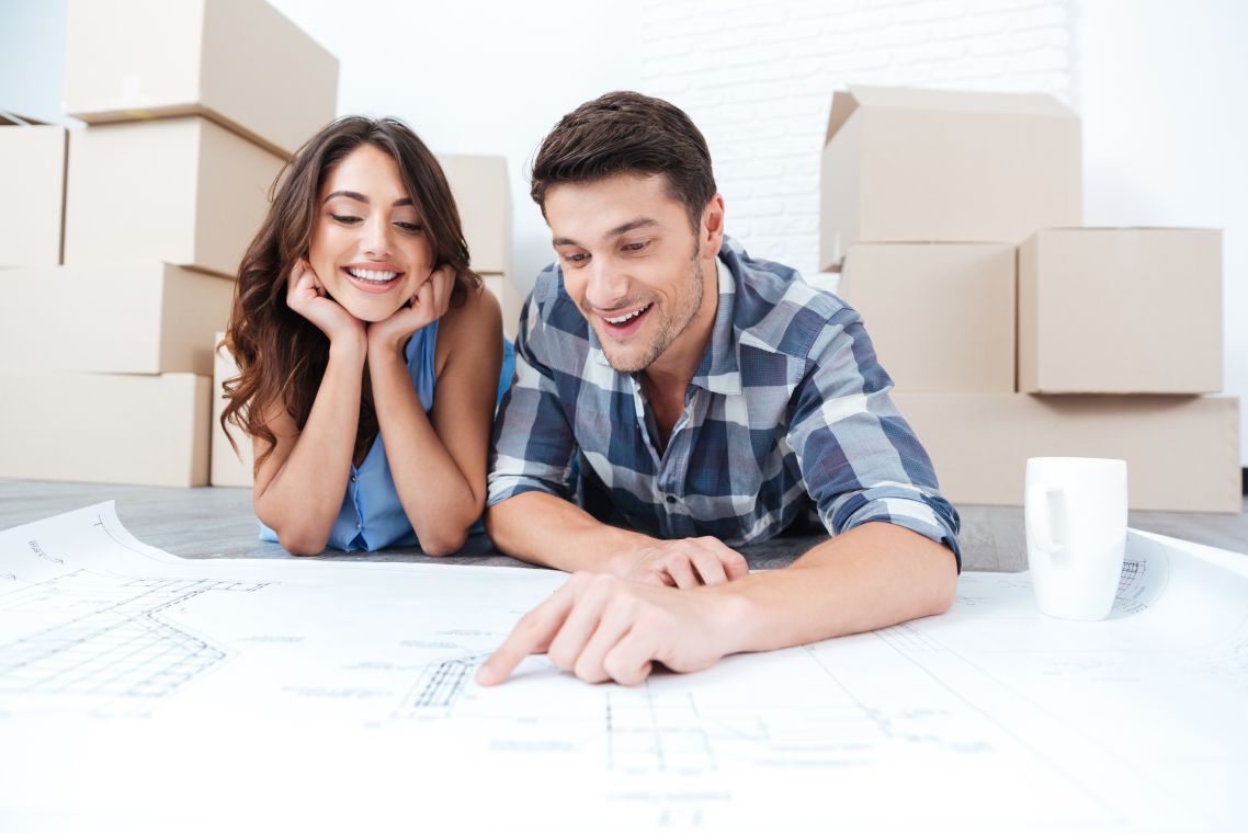 Happy couple looking at new house blueprints at home