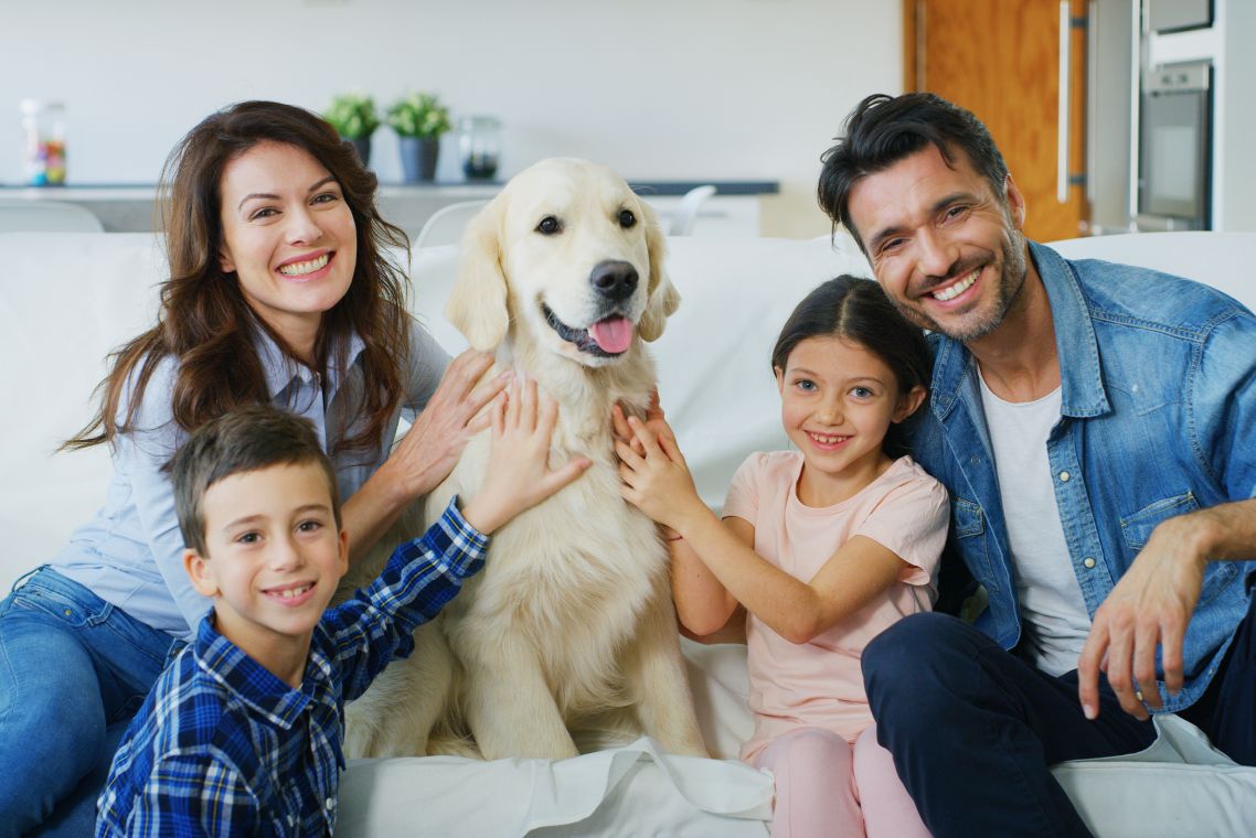 Portrait of happy family with a dog having fun together in living room. Concept of happy family, love for animals, childhood
